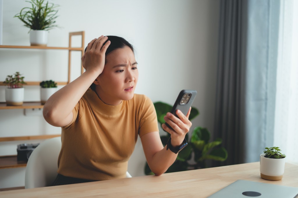 A woman looks stressed while looking at her phone.