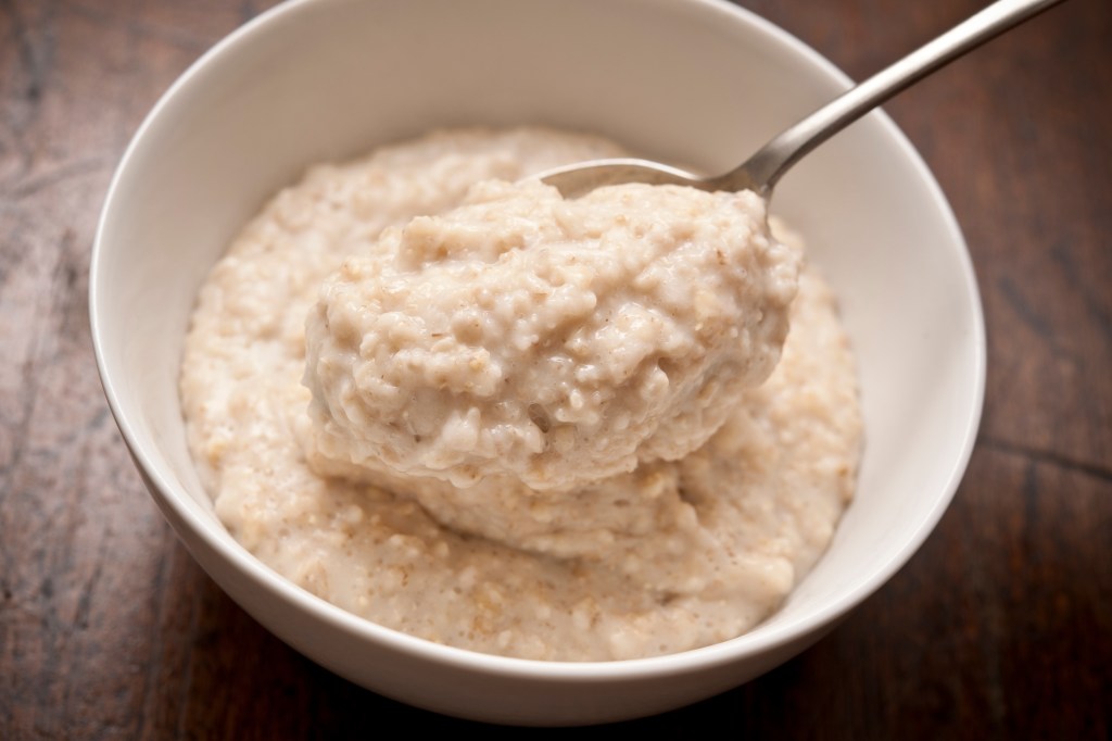 Oatmeal (pictured here in a white bowl) is a good late-night snack because it contains melatonin, releases serotonin, doesn't take long to digest, and helps keep you full throughout the night.