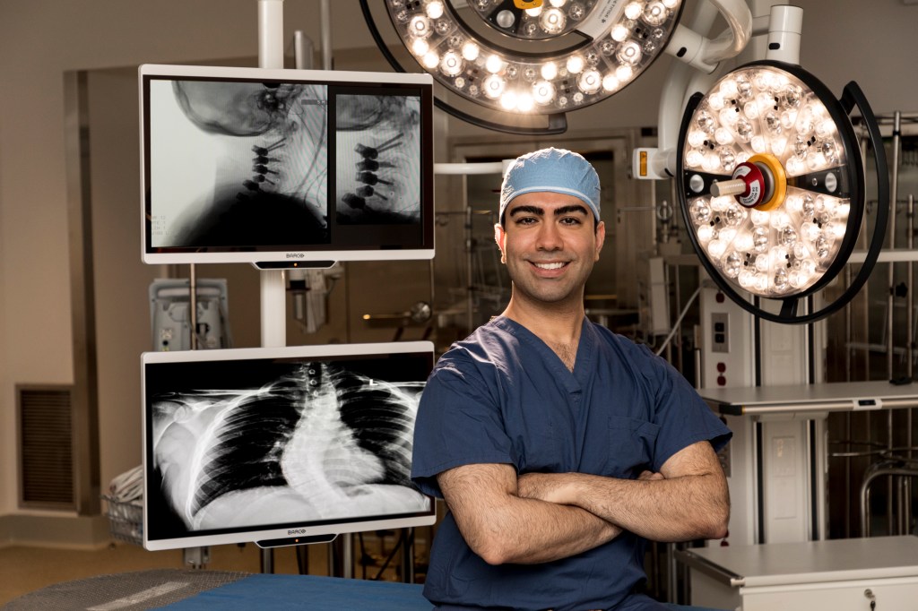 Dr. Jonathan J. Rasouli in a medical setting with X-rays of the spine behind him