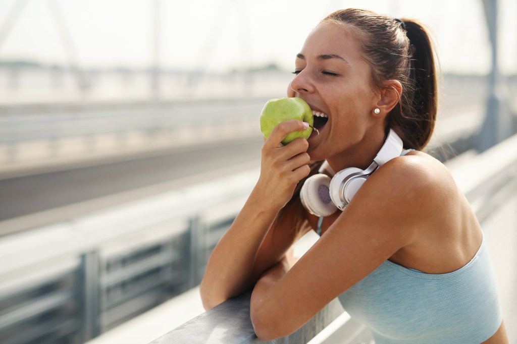 Woman eating an apple while jogging