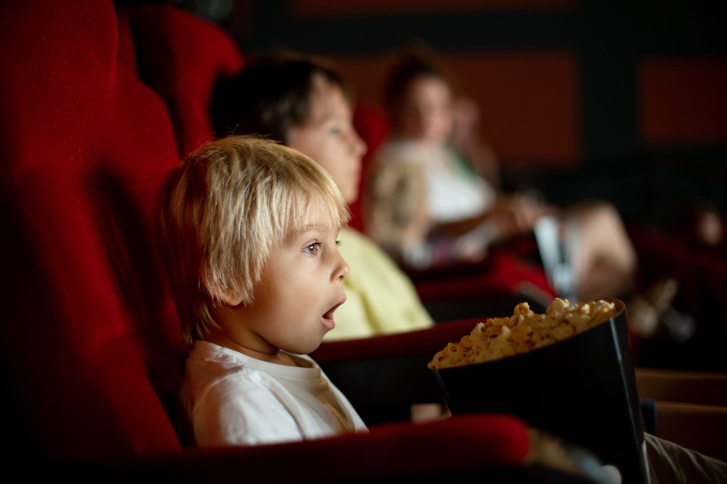 Boy in the cinema enjoying a movie while eating popcorn, with a glimpse of La Parka in the movie.