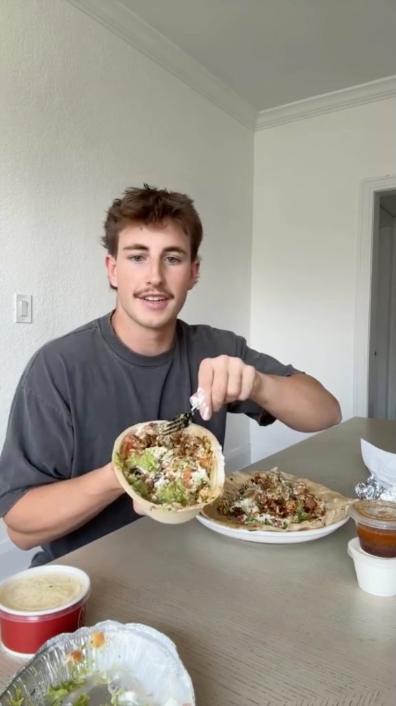 A man holding a customizable Chipotle bowl filled with fresh ingredients