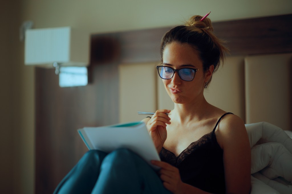 Writing a to-do list lets you take your worries away, so you don't have to think about them while you're trying to sleep. Here, a woman makes notes while sitting in bed.