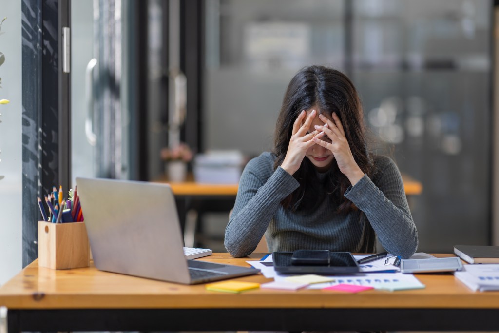 A woman sitting at a table with her hands on her face