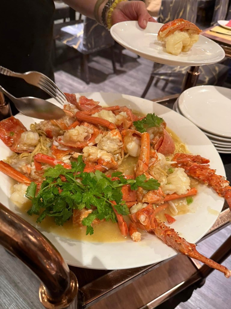 The woman looks bored at Canton Lane Chinese Restaurant with a plate of seafood, including live lobster, on the table