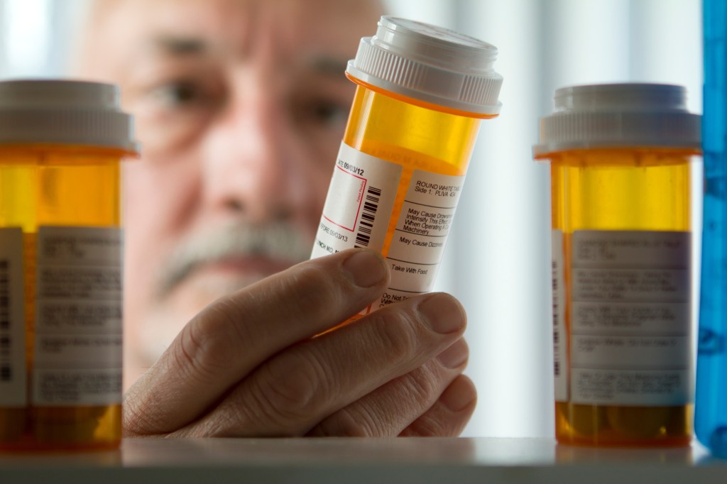 A man reaches into the medicine cabinet to grab a bottle of pills